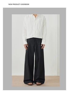 Détail d'une chemise blanche texturée à manches longues et d'un pantalon noir à taille haute