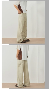 Detail view of khaki wide-leg utility trousers with cargo strap and pocket accents