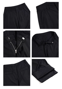 Detail view of black dress pants showing belt loops, metal zipper, and button closure