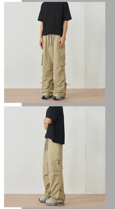 Detail of khaki cargo pants featuring large side flap pockets and adjustable drawstring hem