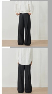 Détail du pantalon plissé noir à jambe large avec un drapé élégant et un design minimaliste