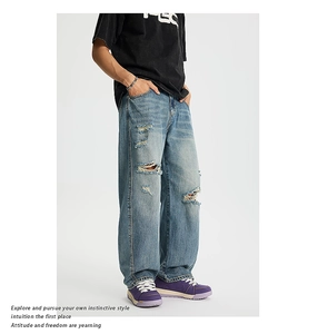 Dettaglio dei jeans azzurri con strappi manuali e lavaggio in stile vintage