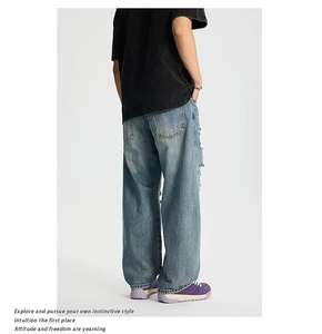 Dettaglio dei jeans lavati blu con strappi laterali ed effetti di sbiadimento a baffo