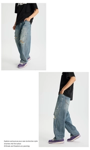 Dettaglio dei jeans azzurri con strappi sulle ginocchia e finitura invecchiata
