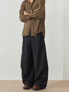 Men's relaxed black wide-leg trousers paired with a vertical striped shirt for casual style