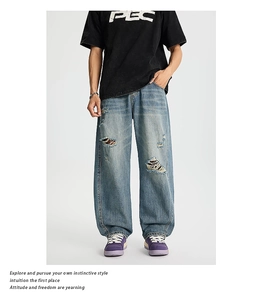Dettaglio di jeans blu vintage a gamba larga con strappi e finitura lavata usurata