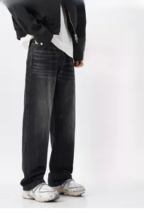Detail showing distressed wash and cat-whisker texture on men's dark grey denim jeans