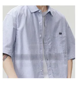 Close-up of blue and white striped cotton fabric texture and pocket detail on short sleeve shirt