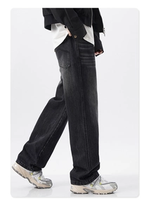 Detail of washed black straight-leg jeans with vintage fading and whisker effects