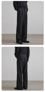 Detailed view of black pleated wide-leg trousers featuring drape fabric and side pocket