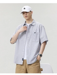 Detail view of blue striped short sleeve shirt with chest pocket and woven brand label