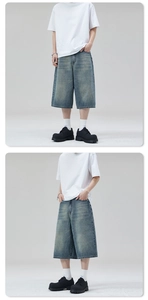 Detail showing loose fit and light blue washed finish of men's denim wide-leg shorts