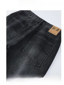 Detail of vintage gray denim jeans featuring a leather back patch and washed texture