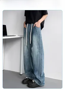 Detail view of washed blue wide-leg jeans with white drawstrings and vertical stitching