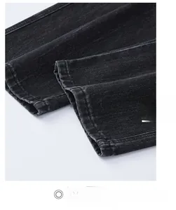 Detailed macro view of the straight leg opening on washed dark gray denim trousers