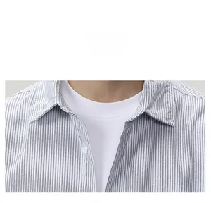 Detail view of a blue and white striped shirt collar with white button and cotton T-shirt