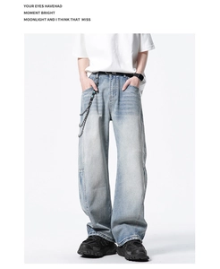 Détail d'un jean en denim bleu clair avec chaînes métalliques et perles décoratives