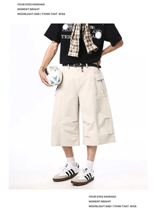 Detailed view of cream-colored cargo shorts featuring large flap pockets and a loose fit