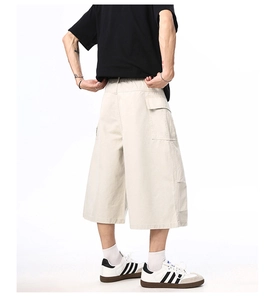 Detail of loose-fit cargo shorts for men with large side pockets and elastic waist in beige