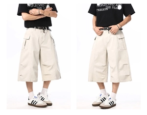 Detail of loose-fit beige cargo shorts showing spacious side pockets and pleated stitching