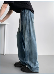 Detail view of wide-leg blue washed jeans with side stripes and drawstring waist