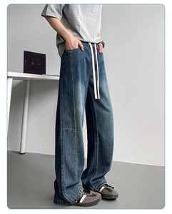 Detail of dark blue wide-leg jeans with long white drawstring and relaxed straight fit