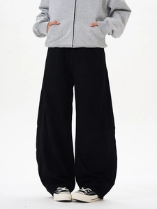 Détail du pantalon large noir oversize avec un design streetwear déconstruit et fluide