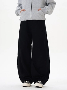 Détail du pantalon large noir oversize avec silhouette drapée et texture en coton sergé