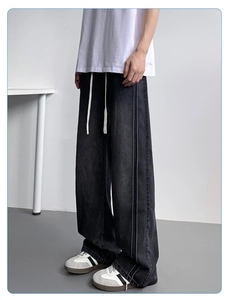 Close-up of gray wide-leg denim jeans featuring side stripes and white drawstring details