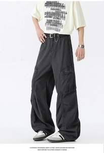Detail of black baggy cargo pants featuring side flap pockets and metal chain belt
