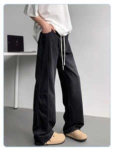 Detail view of black wide-leg denim pants with contrast stitching and elastic drawstring waist