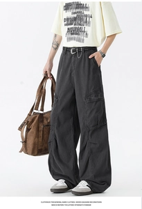 Detail of dark charcoal cargo pants featuring oversized 3D flap pockets and metal chains