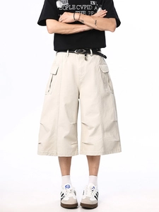 Men's beige cargo shorts with wide leg fit and layered pleat hem detail on white background