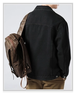 Detail of vintage brown leather backpack with metal buckles worn over a denim jacket