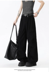Detail shot of black loose-fit cargo pants with large utility pockets and fabric texture