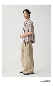 Detail of khaki wide-leg trousers and plaid short-sleeve shirt in a retro street style