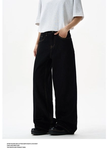 Detailed view of black wide-leg jeans with contrasting yellow stitching and high waist cut