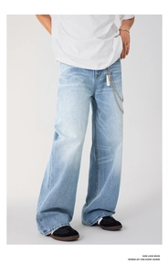 Close-up of light blue washed denim jeans featuring a vintage finish and silver metal chain