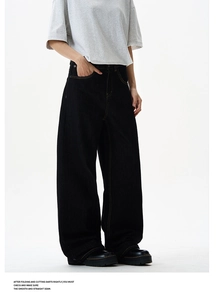 Detail of loose fit black denim jeans with high-contrast orange stitching and wide leg cut