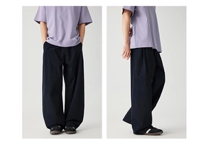 Detail view of black wide-leg trousers with pleated curved cut and loose street style fit