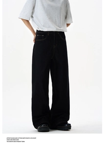 Detail of high-waisted black wide-leg denim pants with contrast yellow stitching