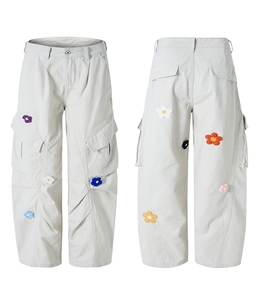 Détail de la broderie florale 3D colorée sur le tissu du pantalon cargo beige