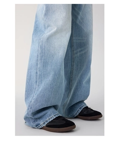 Detail of light blue washed denim jeans with vintage texture and distressed hem finish