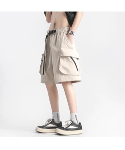 Detail of loose beige cargo shorts with large side pockets and adjustable nylon belt
