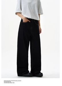 Detail of washed black wide-leg jeans with yellow topstitching and retro loose fit