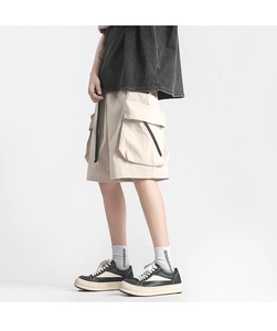 Detail of beige cargo shorts featuring large flap pockets and functional zipper elements