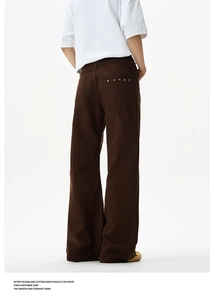 Detail of brown wide-leg trousers featuring metal rivets on back pockets and heavy cotton