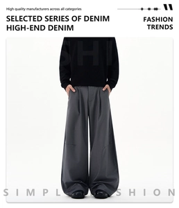 Detail of dark grey wide-leg trousers with elegant pleats and heavy drape fabric