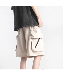 Detail view of khaki cargo shorts featuring large side pockets and black diagonal zippers