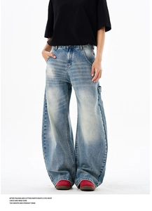 Detail of vintage washed blue wide-leg jeans with whiskering and distressed texture